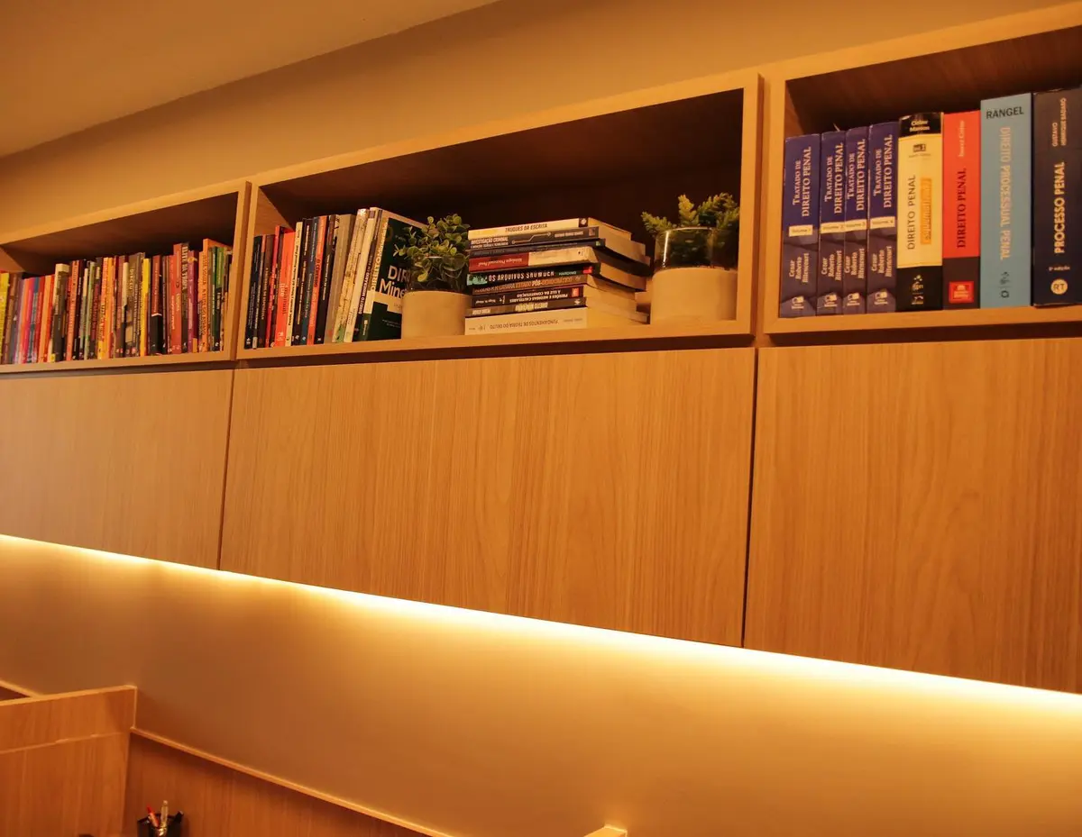 Estante de madeira com livros jurídicos e iluminação embutida no escritório